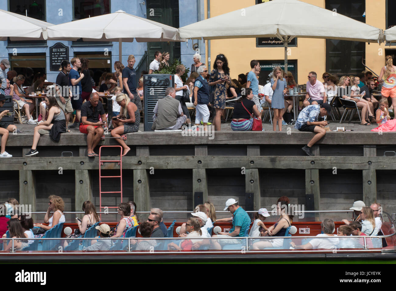 La foule la foule à bord de Nyhavn, Copenhague, Danemark et regarder passer les touristes sur un bateau au-dessous d'eux. Banque D'Images