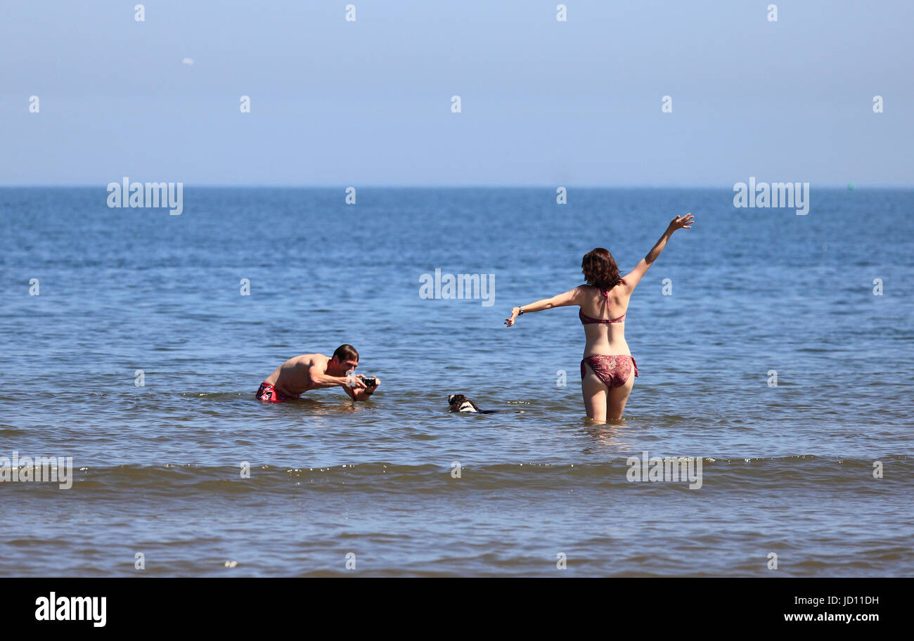Brancaster, Norfolk, Angleterre, Royaume-Uni. 18 juin 2017. Jeune couple de prendre des photographies dans la mer avec leur chien. Crédit : Stuart Aylmer/Alamy Live News Banque D'Images