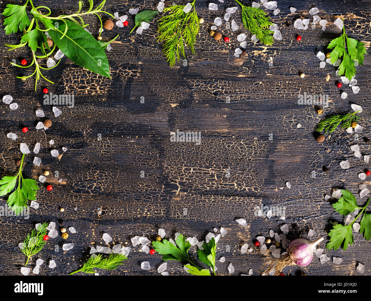 Vue de dessus d'épices couronne de poivrons secs, sel de mer, de la verdure et de l'ail sur différentes fissures fond noir Banque D'Images