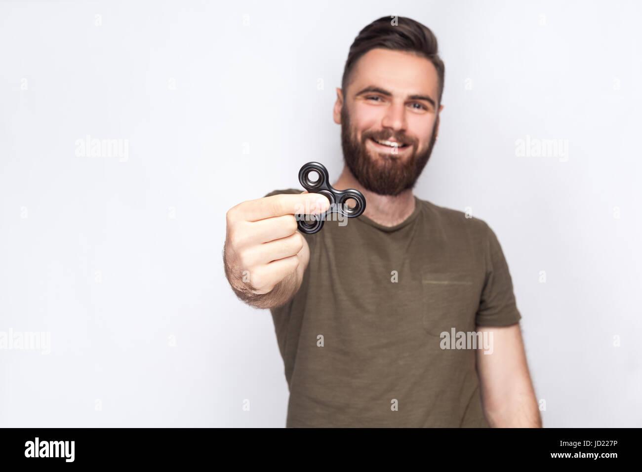 Young man holding et jouer avec fidget spinner. looking at camera. studio shot sur fond blanc. Banque D'Images