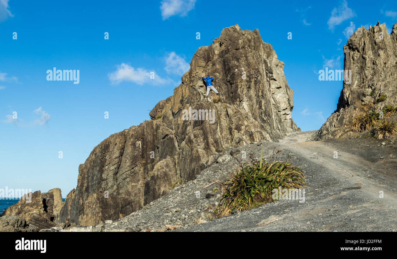 Homme climming jusqu'Kopahou Devils Gate, te réserver, sur la côte sud de la Nouvelle-Zélande. Banque D'Images
