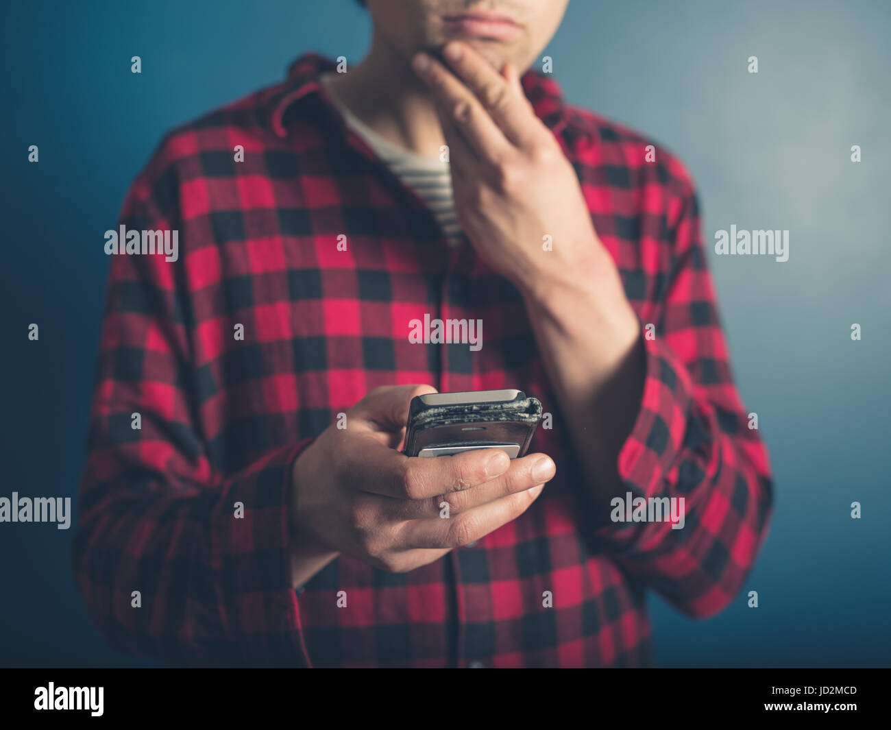 Un jeune homme portant un hippie chemise bûcheron utilise son téléphone intelligent Banque D'Images