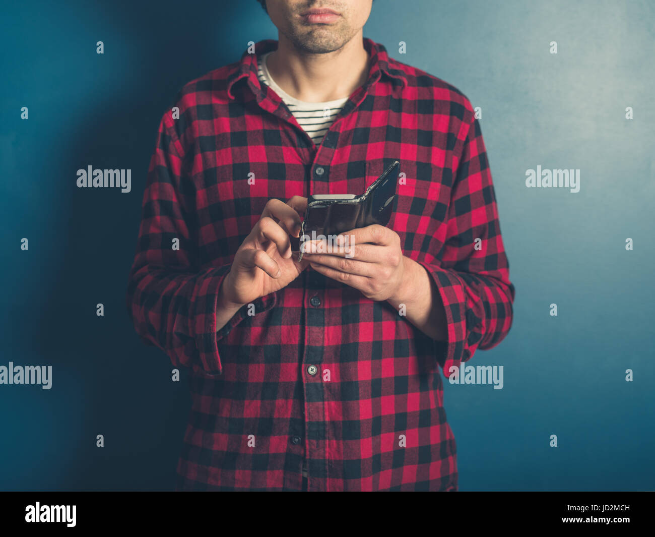 Un jeune homme portant un hippie chemise bûcheron utilise son téléphone intelligent Banque D'Images
