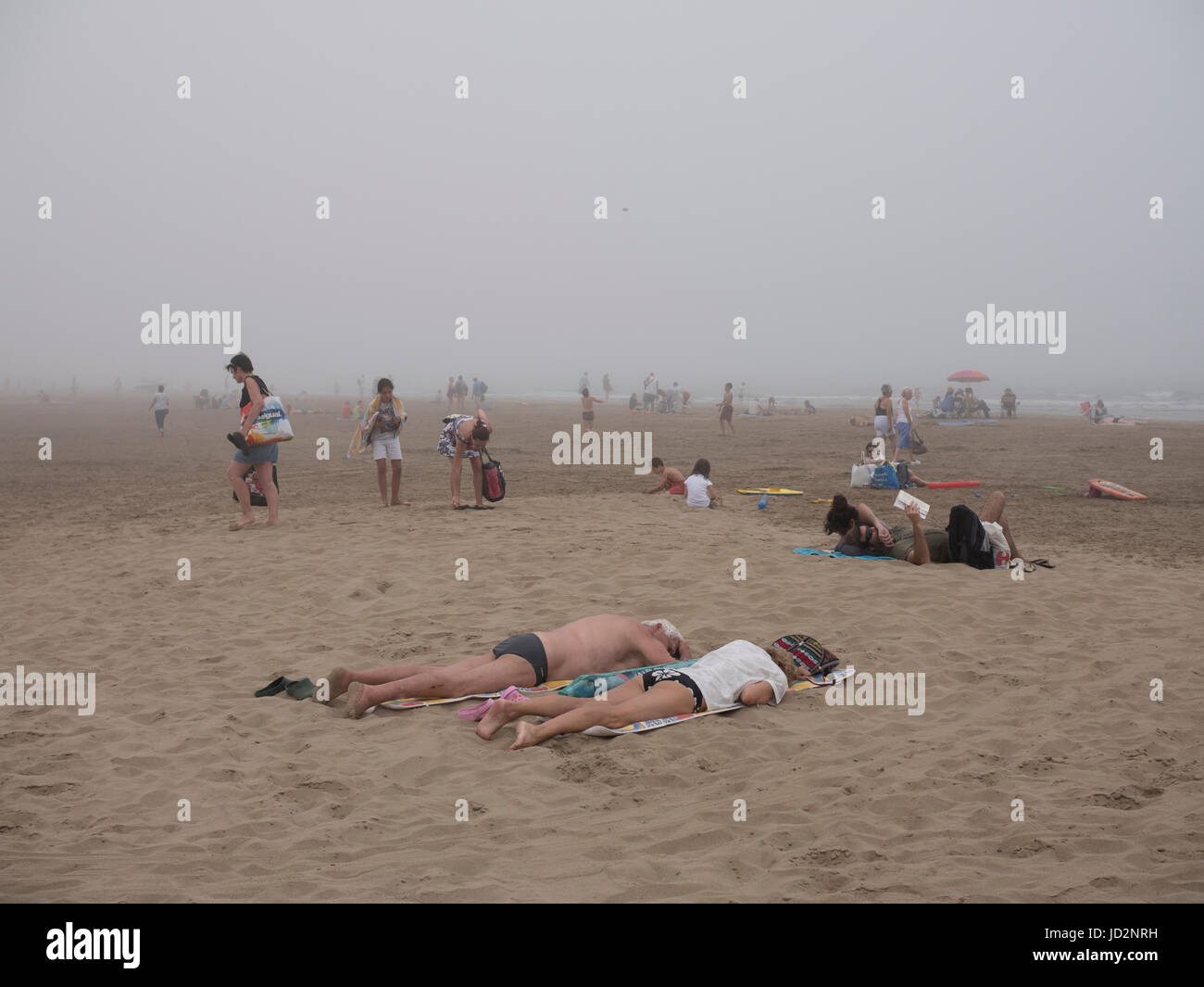 Les baigneurs et les familles Sun Laissez un beach se dépêcha comme un brouillard d'eau de mer froide. Banque D'Images