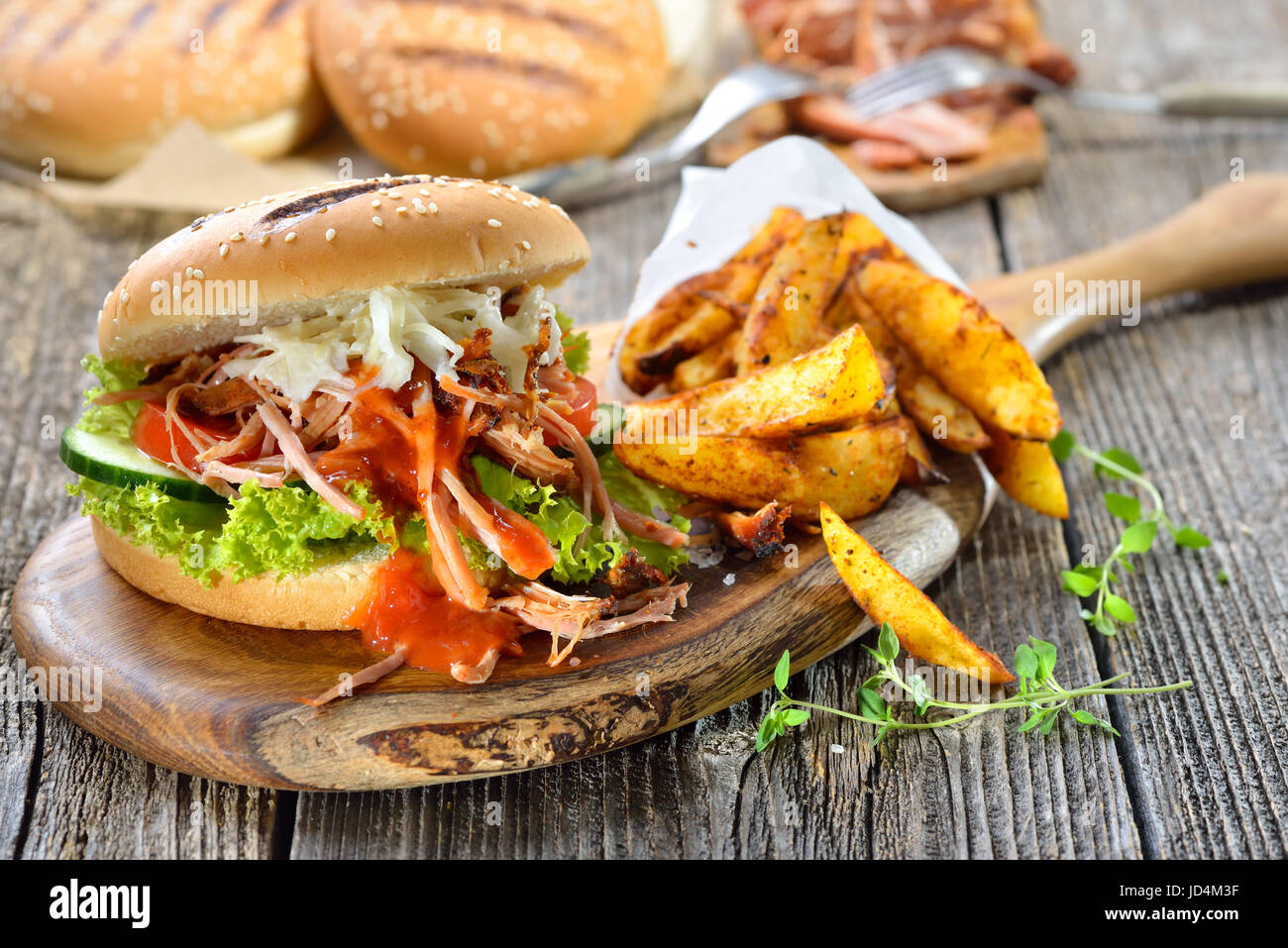 Sandwich de porc barbecue avec salade de chou, sauce BBQ chaud et les quartiers de pommes de terre dans un sac de papier servi sur une table en bois Banque D'Images