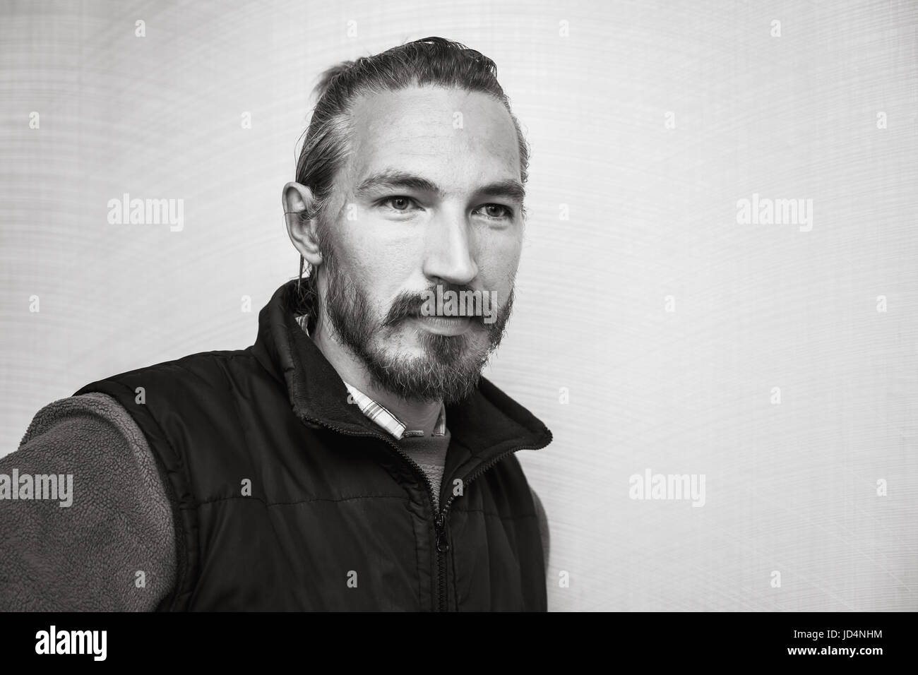 Le noir et blanc portrait de jeune homme asiatique barbu fond mur gris ci-dessus Banque D'Images