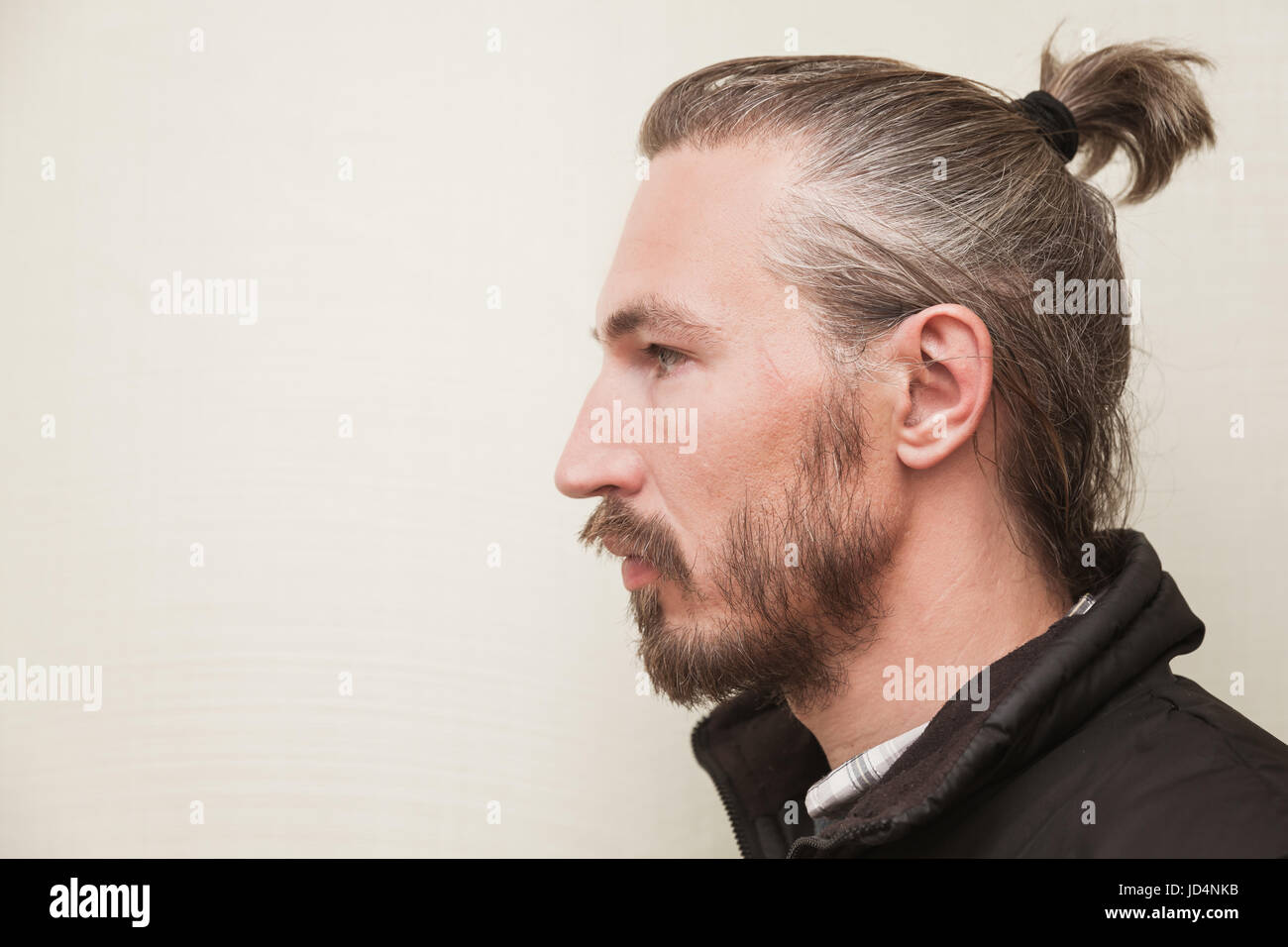 Profile portrait of young Asian man barbu gris clair au-dessus de wall background Banque D'Images