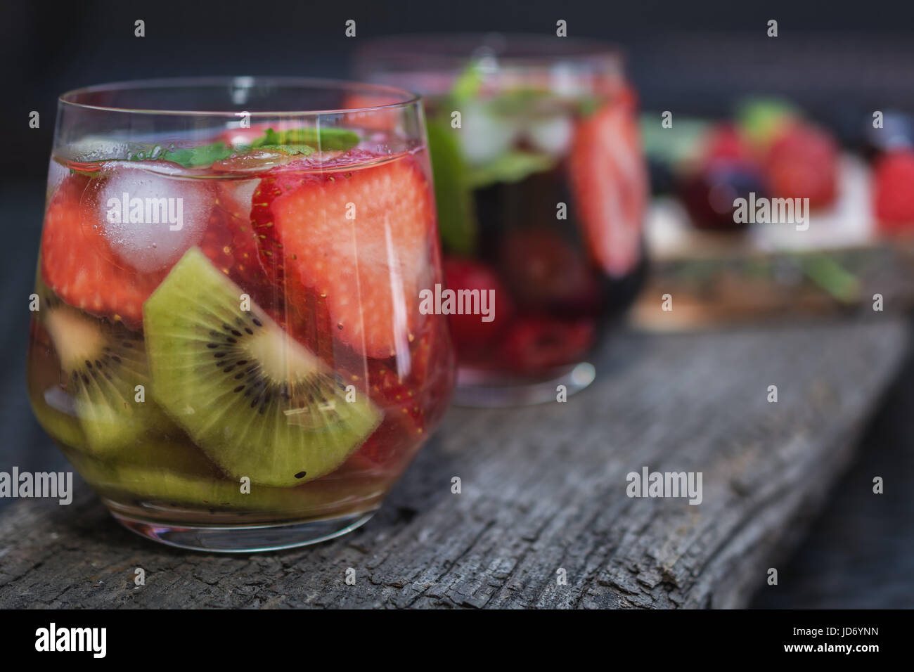 Verres de l'eau de fruits avec divers ingrédients présentés sur un arbre dur Banque D'Images