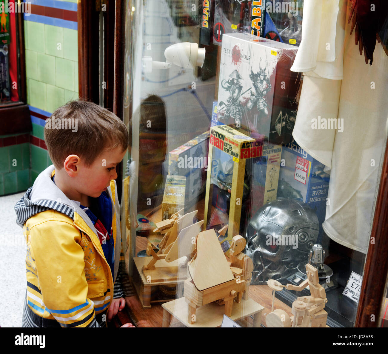 Un jeune garçon (5 ans) à la recherche dans à la fenêtre d'un magasin de jouets dans la royal Arcade, Norwich, Norfolk, Angleterre Banque D'Images