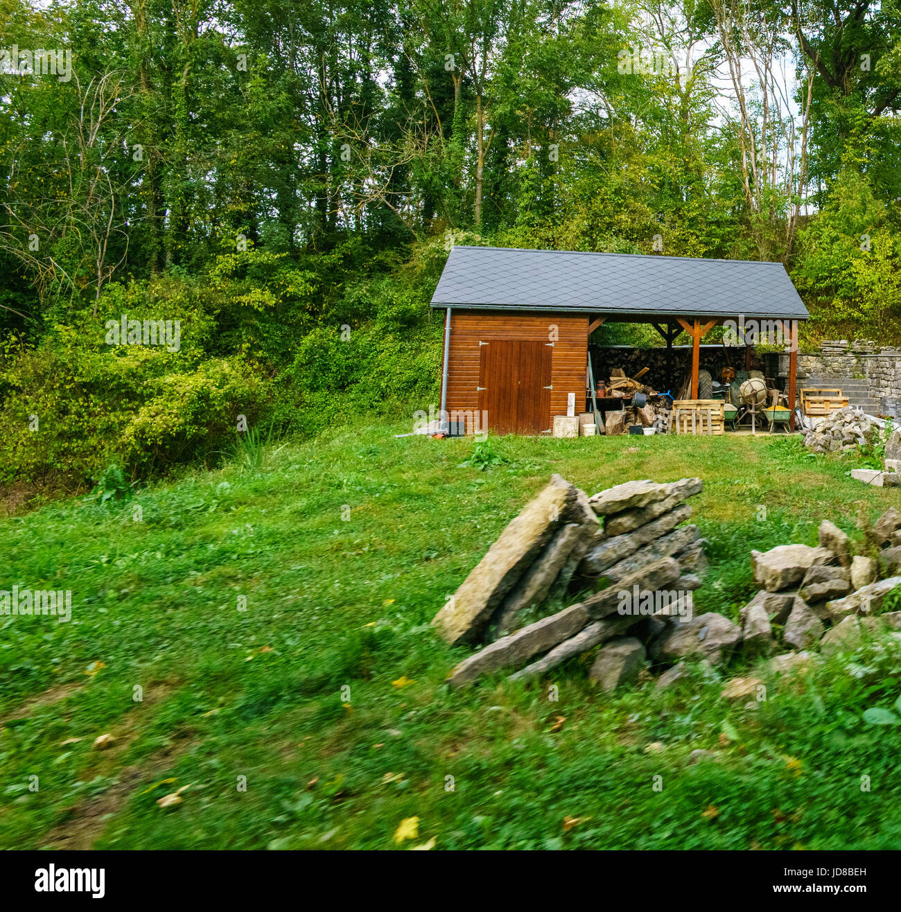 Petite cabane en bois avec des arbres derrière, des tas de rochers en premier plan. Belgique europe Banque D'Images