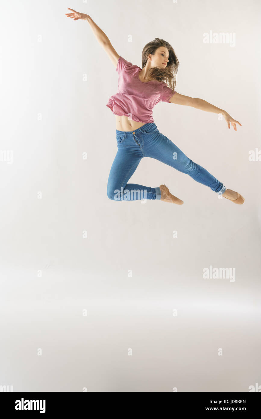 Ballerine femme sautant en l'air de porter des vêtements décontractés, studio shot. caucasian monter assez maigre athletic Banque D'Images
