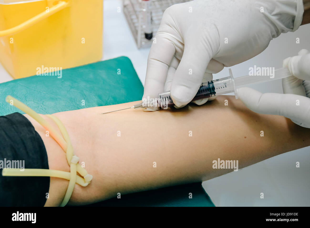 Médecin ou infirmière dans les mains des gants médicaux à l'aide de seringue aiguille bleu dessin échantillon de sang au bras du patient à l'hôpital. Scientist obtenir le sang tirage d'hémo Banque D'Images