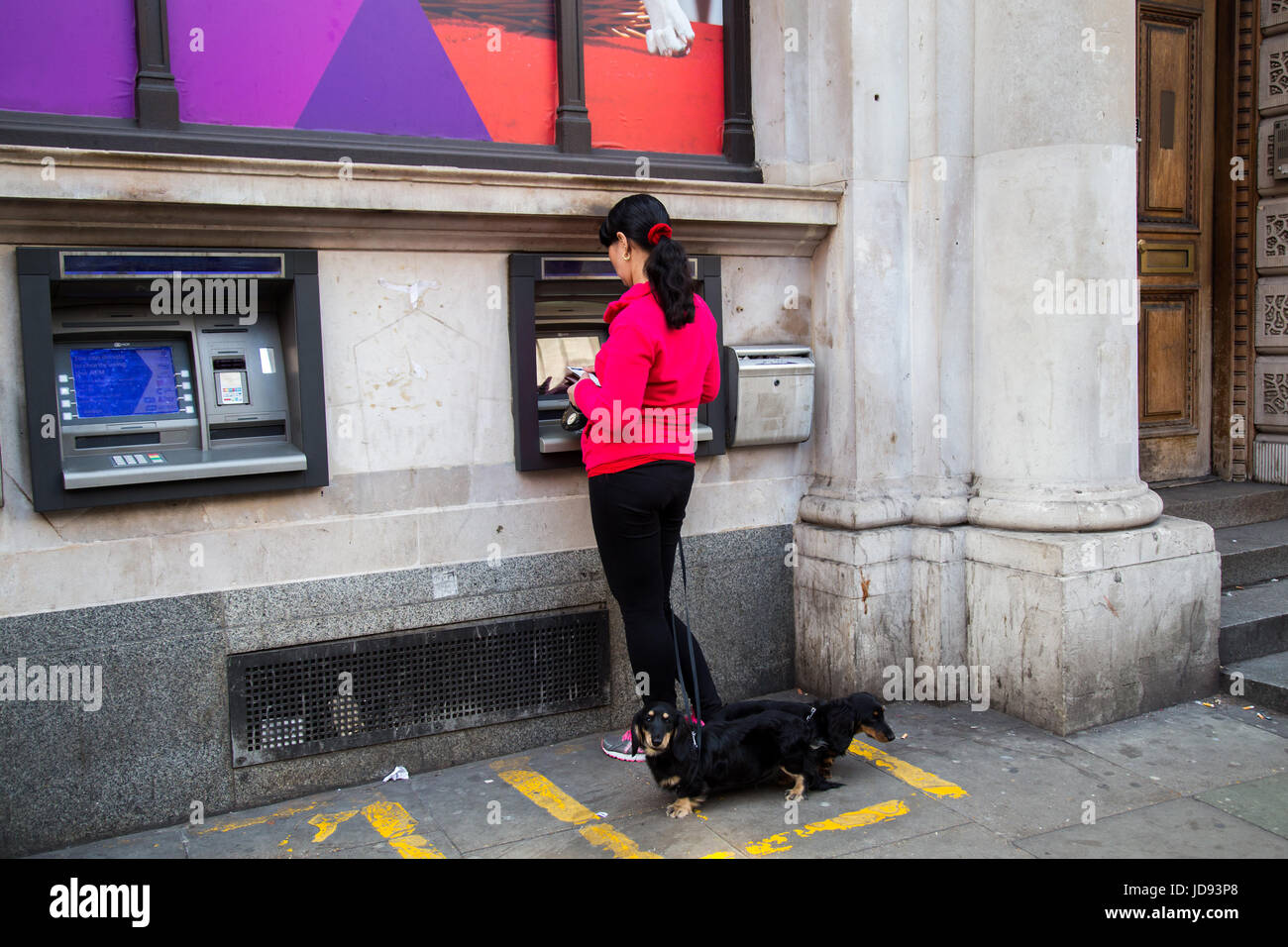 Londres, Royaume-Uni - 08 Avril 2015 : une femme se tient debout par un distributeur automatique avec des chiens Banque D'Images