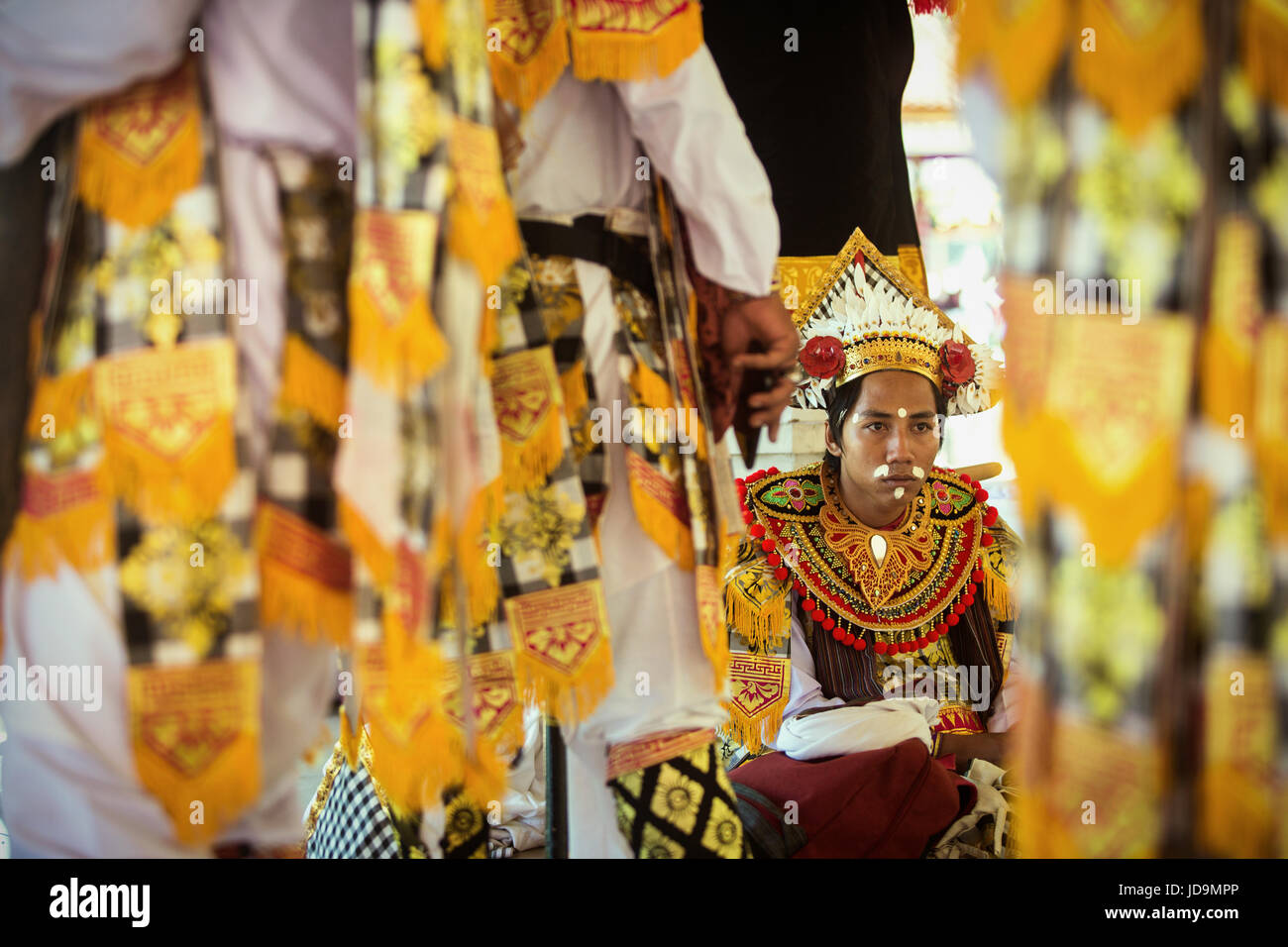 Selective focus on interprète masculin balinais vêtus de beaux costumes traditionnels colorés et ornés vu par groupe comme il attend pour effectuer Banque D'Images