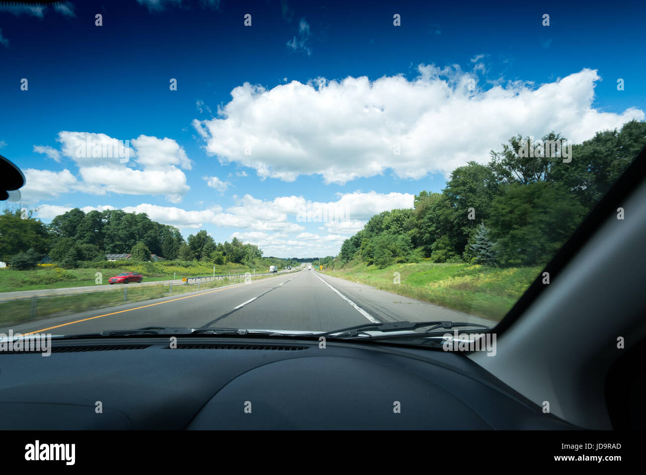 Vue sur rue principale vue à travers pare-brise de voiture avec des nuages blancs dans le ciel. 2016 urban city United States of America Banque D'Images