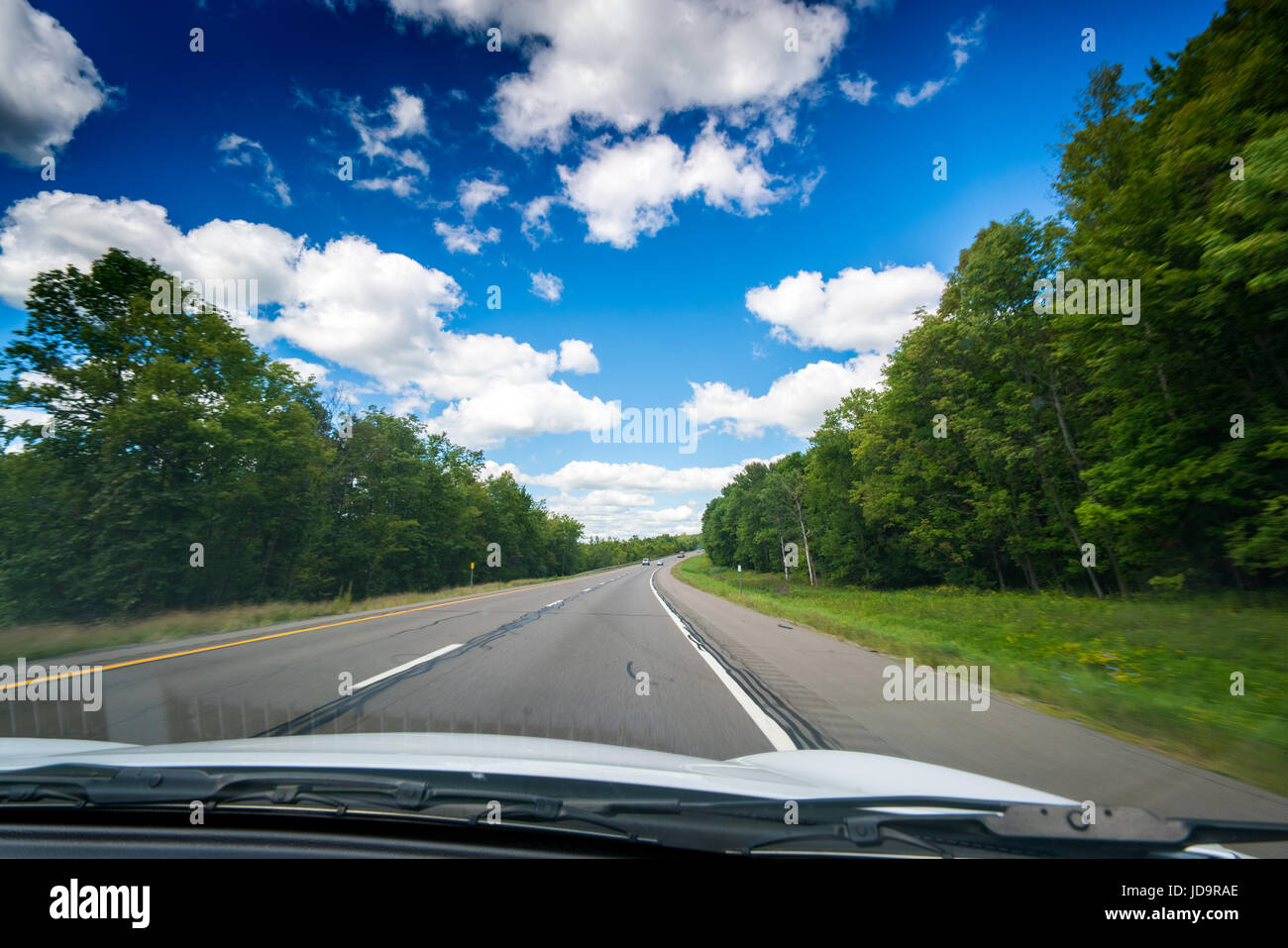 Vue sur rue principale vue à travers pare-brise de voiture avec des nuages blancs dans le ciel. 2016 urban city United States of America Banque D'Images