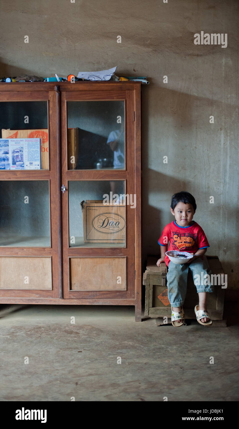 PAKSE, Laos, le 14 août : un petit garçon assis Laos manger dans la chambre de Pakse, Laos le 14 août 2010 Banque D'Images