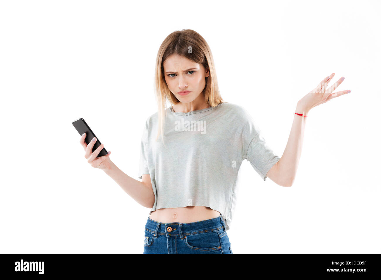 Portrait of a young girl holding confus et haussant les épaules de téléphone mobile plus isolé sur fond blanc Banque D'Images