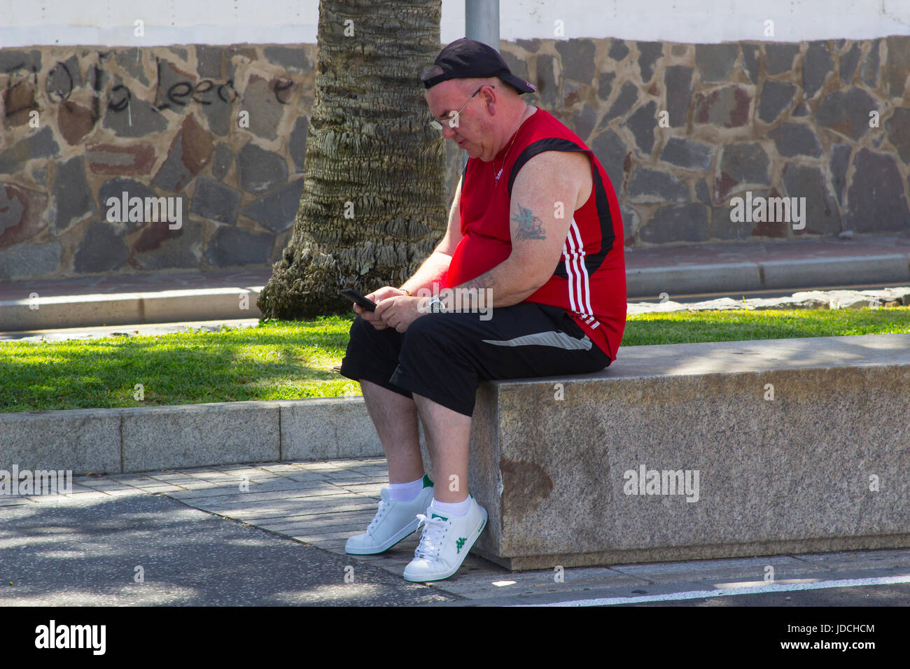 Un touriste à Playa Las Americas à Teneriffe prend une pause et rattrape ses messages texte et e-mails sur son téléphone mobile Banque D'Images