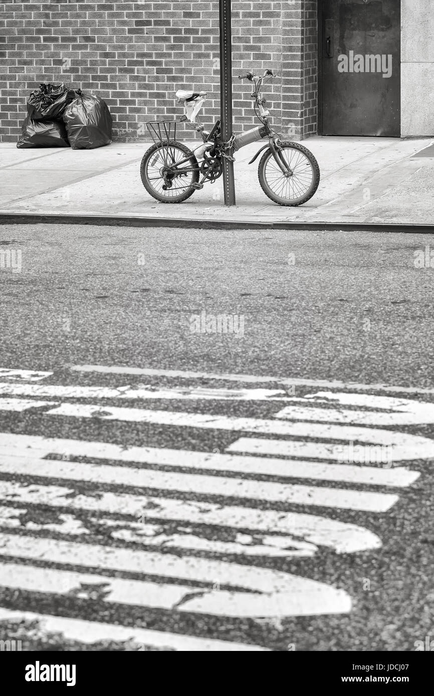 Un vieux vélo verrouillé sur un poteau de signalisation de la rue dans le quartier chinois, la ville de New York, USA. Banque D'Images
