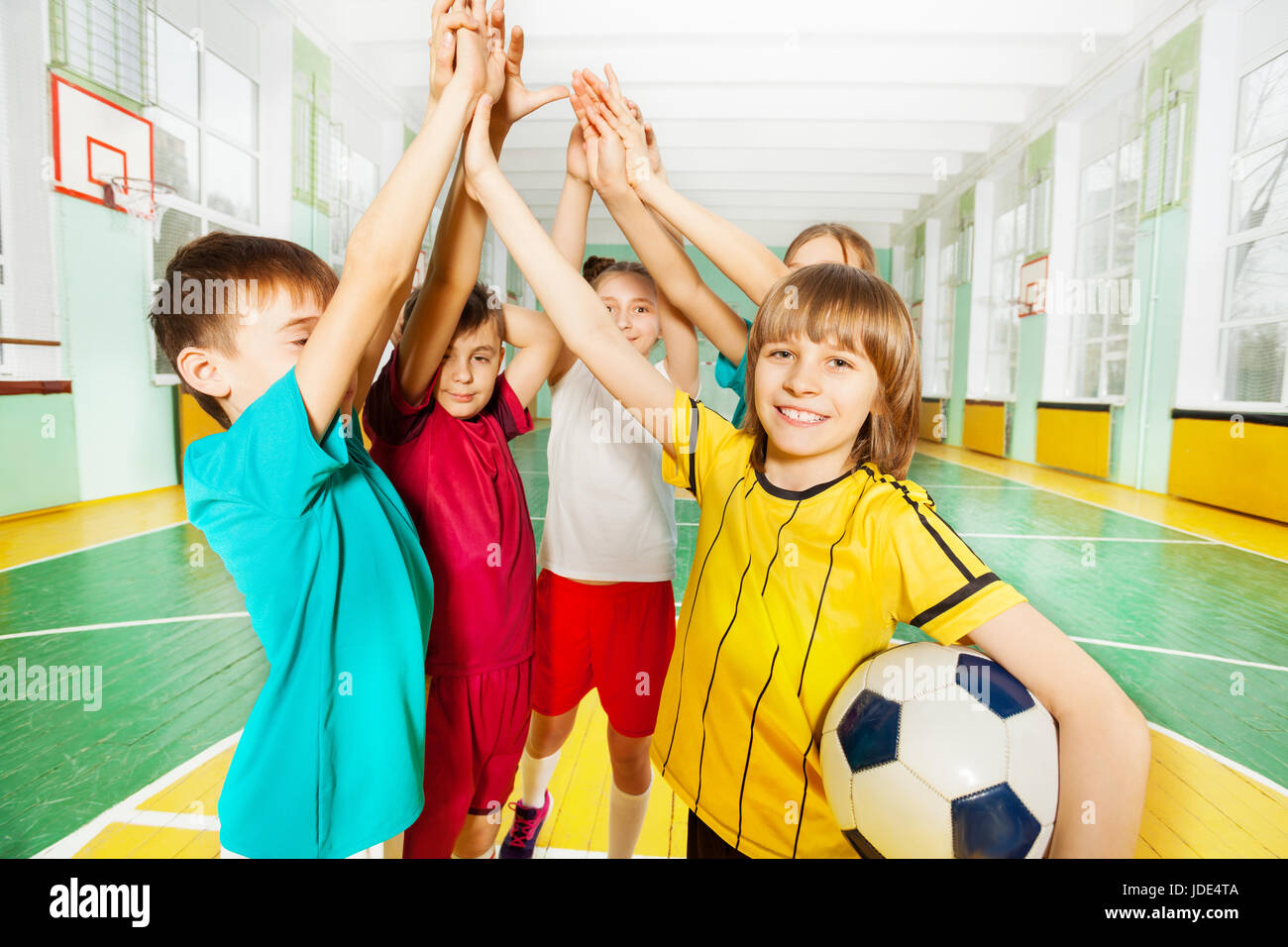 Portrait de garçons et filles préadolescentes, heureux gagnants de football, offrant un rapport dans cinq sports hall Banque D'Images