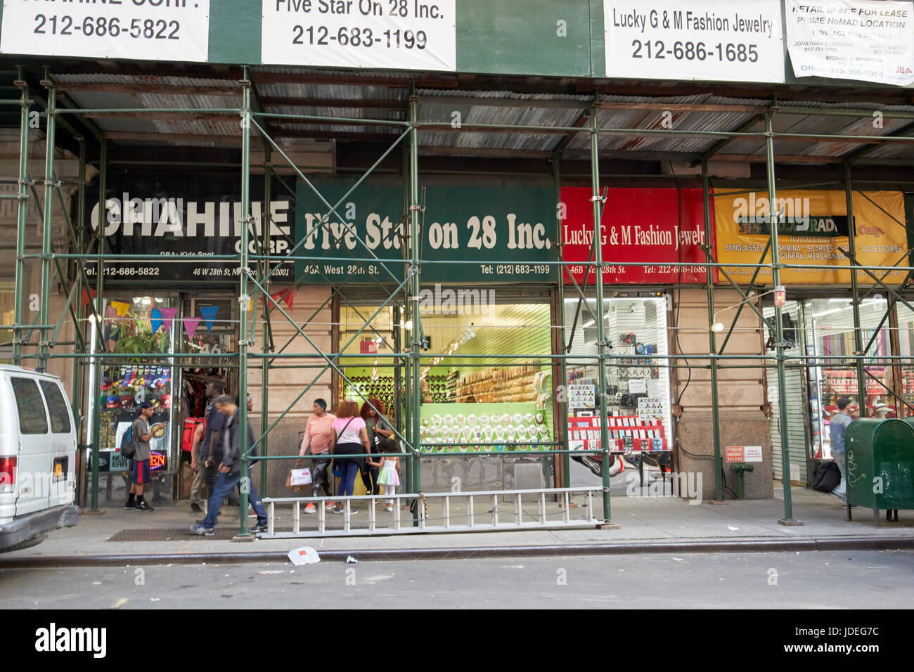 Les échafaudages sur un trottoir à l'extérieur de petits magasins de mode bon marché importés nomad New York City USA Banque D'Images