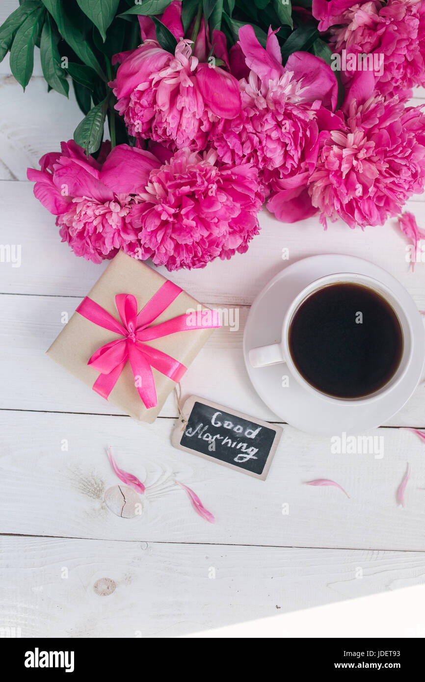 Fleurs de pivoine rose,gift box , tasse de café et note qu'une bonne matinée sur table rustique blanc à partir de ci-dessus, le petit-déjeuner sur la fête des mères, ou jour de l'été Femmes .fl Banque D'Images