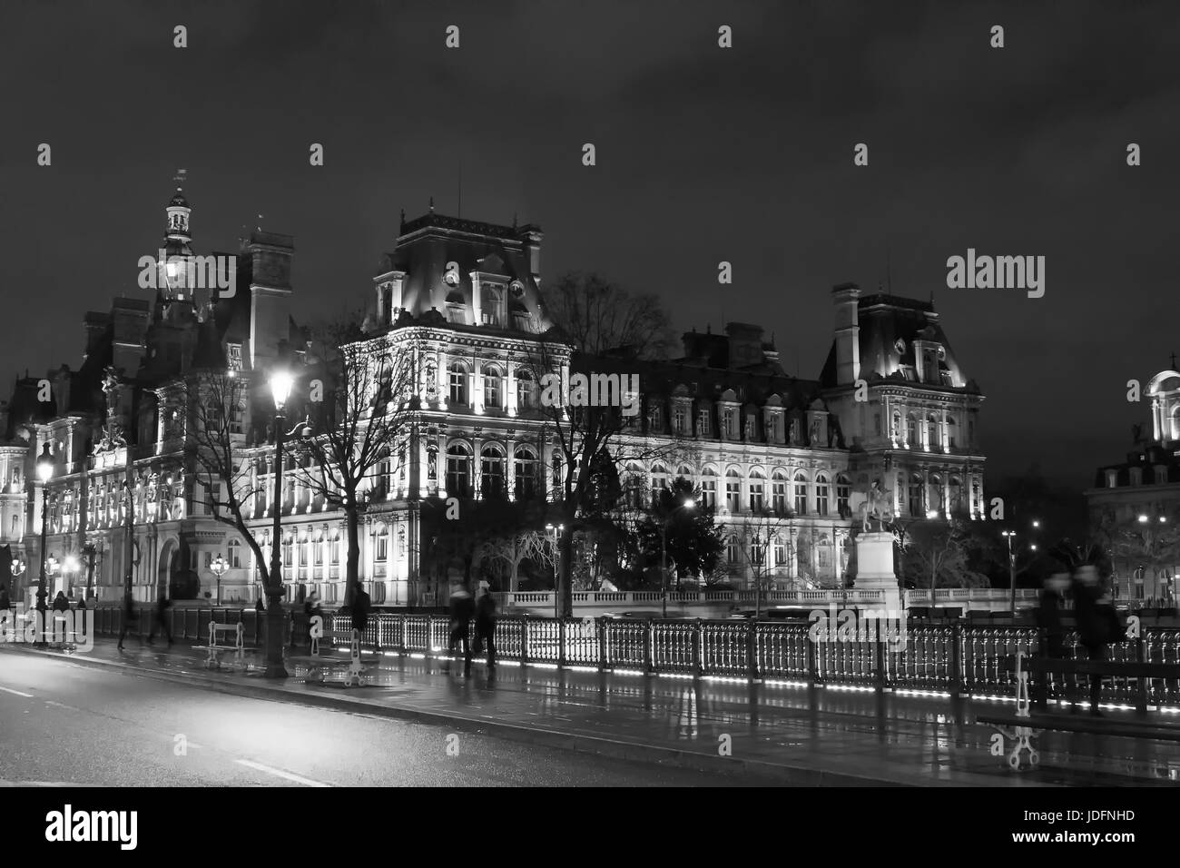 Image en noir et blanc de gens à pied en mouvement flou sur le pont près de l'Hôtel de Ville la nuit à Paris l'hiver. Banque D'Images