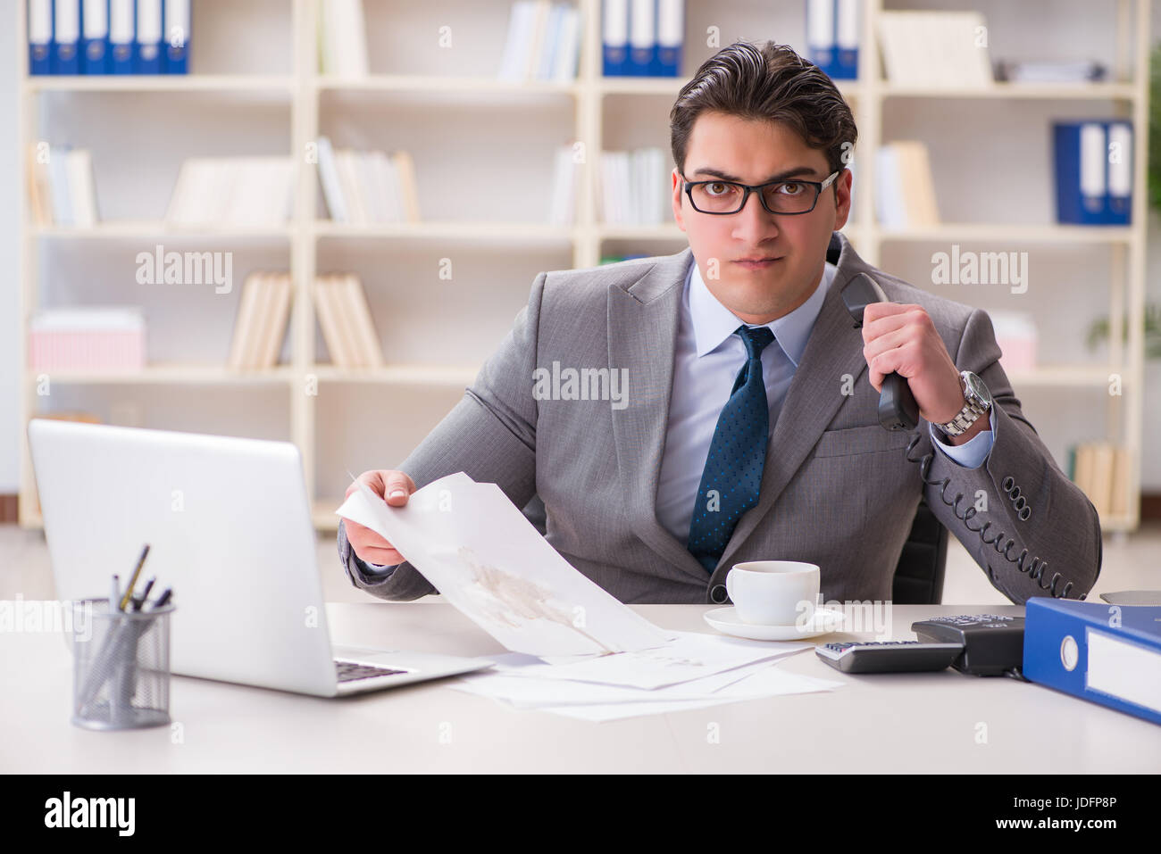 Businessman de renverser du café sur des documents importants Banque D'Images