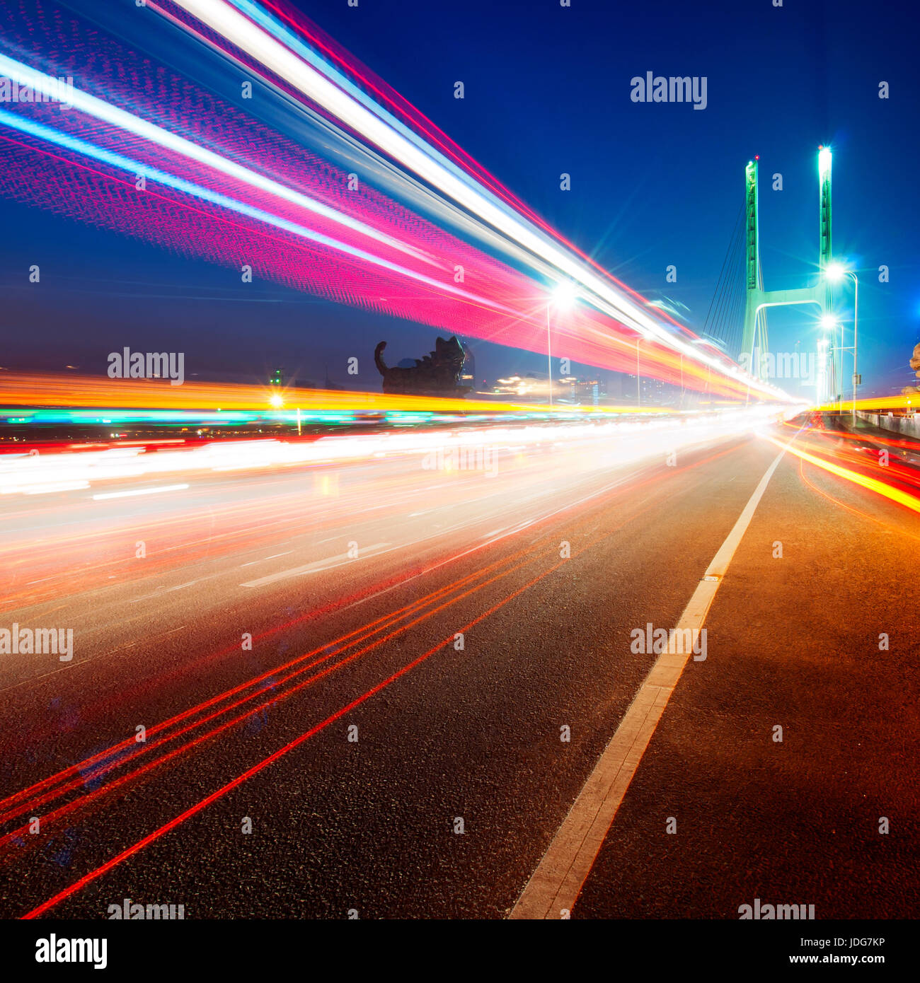 La lumière des voitures traine sur le pont moderne au crépuscule Banque D'Images