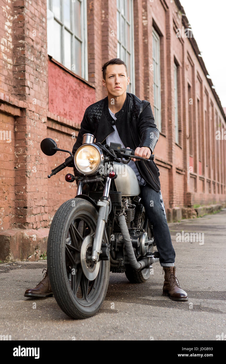 Beau rider biker type en blouson de cuir s asseoir sur un style classique moto cafe racer et se projeter dans l avenir. En fait sur commande de velo vintage gara Photo Stock