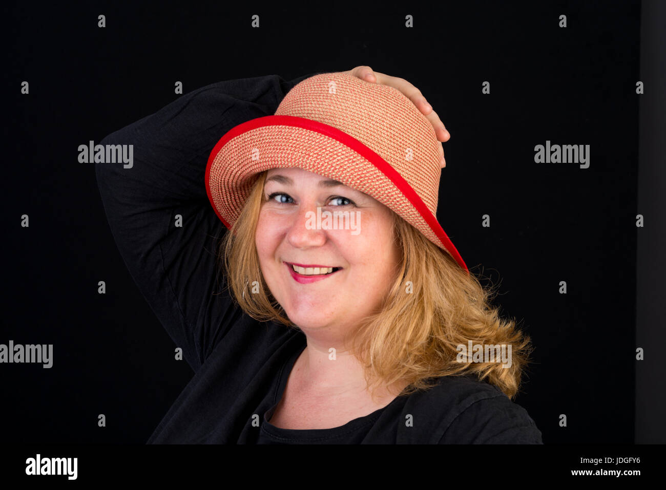 Portrait of a happy belle lumière européenne surpondérés red haired femme posant avec une red hat - studio shot sur fond noir Banque D'Images