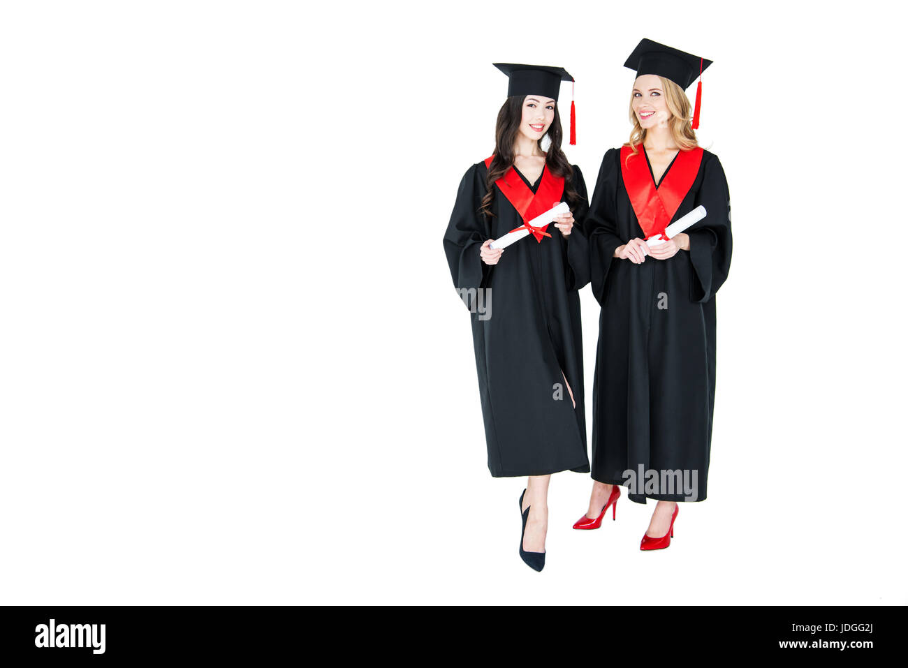 Deux professionnels des jeunes femmes en robes académiques mortarboards holding diplomas Banque D'Images