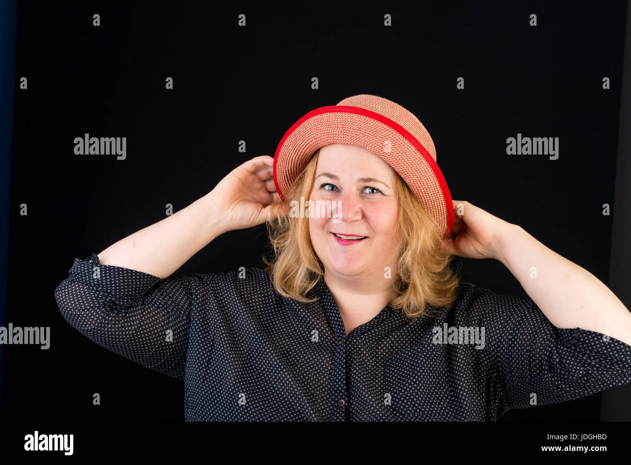Portrait of a happy belle lumière européenne surpondérés red haired femme posant avec une red hat - studio shot sur fond noir Banque D'Images