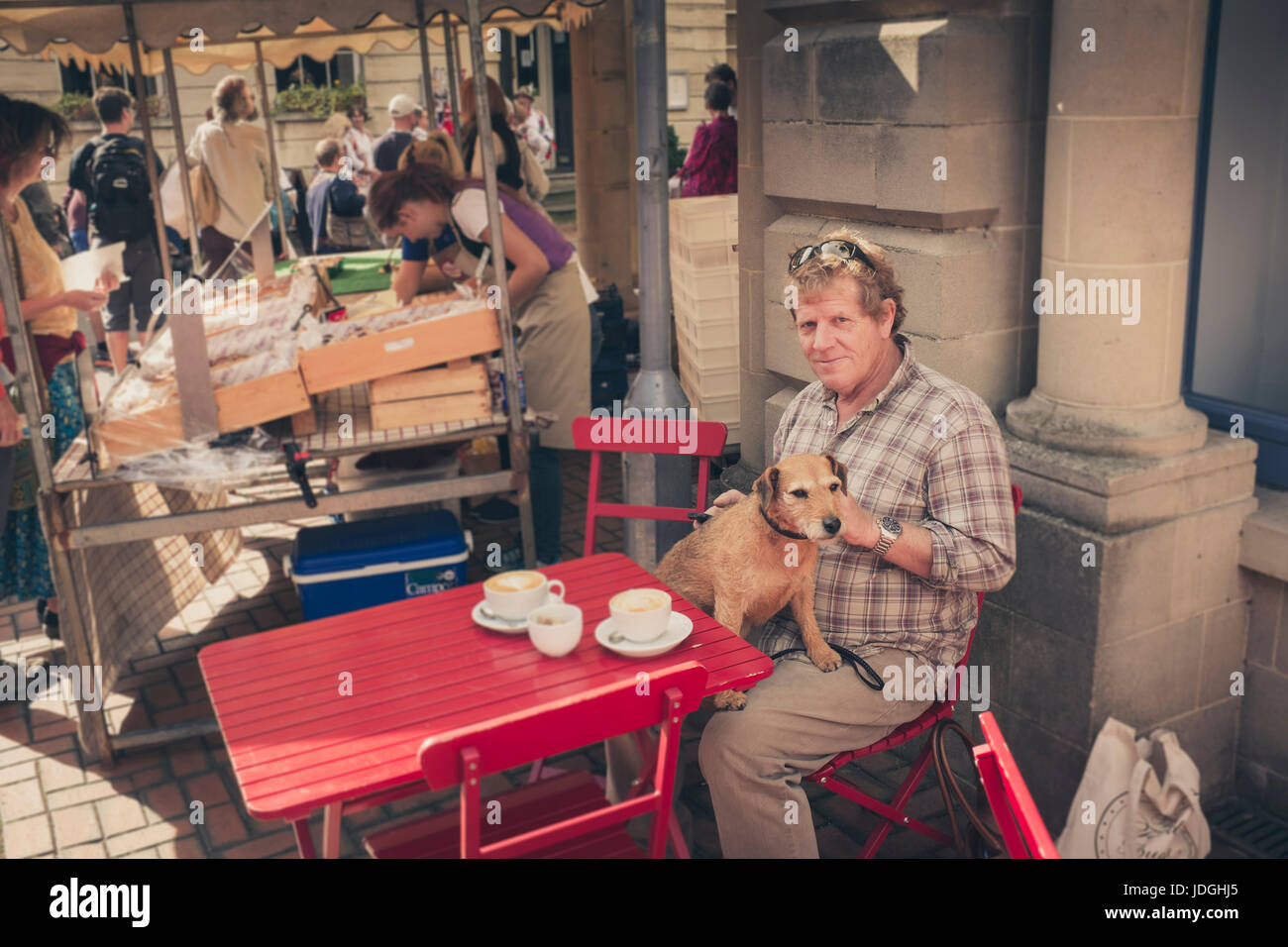 Un homme avec un chien à la terrasse d'un café, le marché des producteurs de Stroud, Gloucestershire, Royaume-Uni Banque D'Images