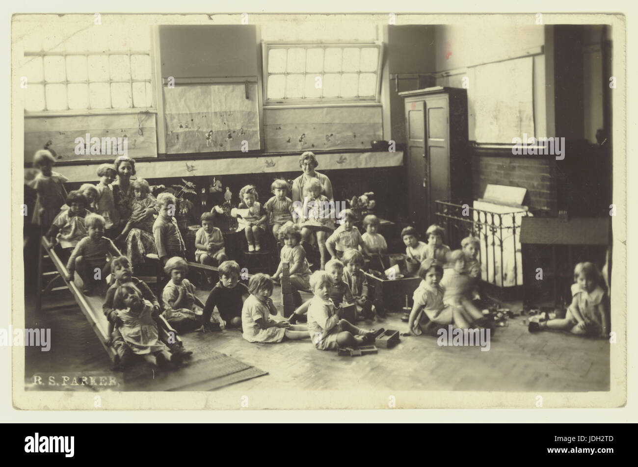 Années 1920 Carte postale de Saint Andrews School, Homer Street, Manchester - nourrissons ou enfants maternelles dans la salle avec l'équipement de jeux, UK Banque D'Images