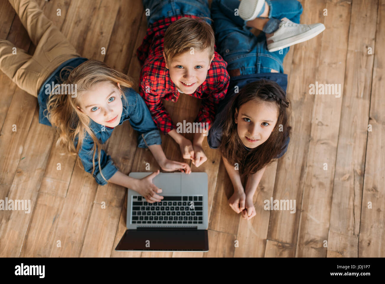 Vue de dessus de petits enfants à l'aide d'ordinateur portable à la maison numérique Banque D'Images