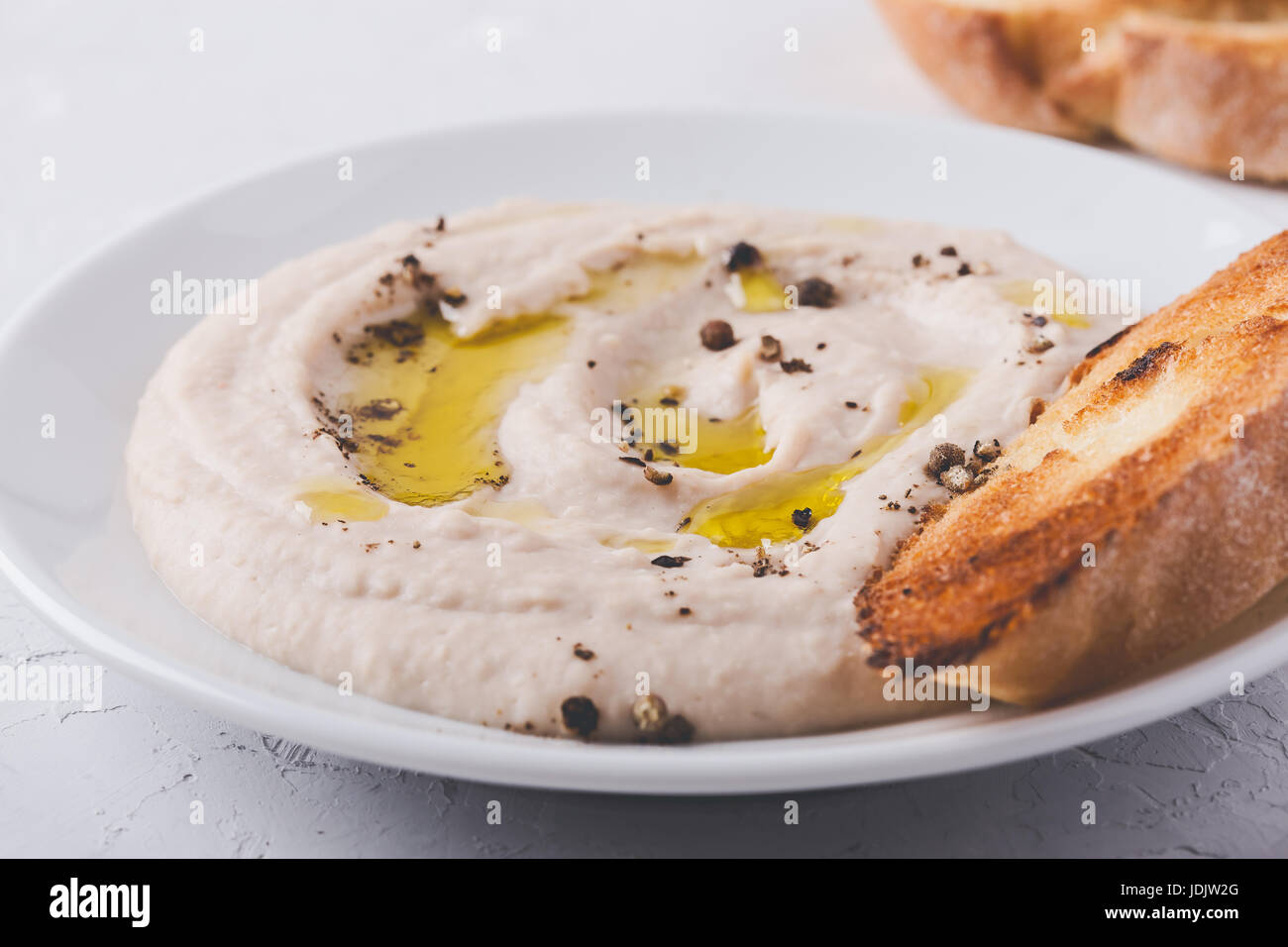 Houmous fait maison avec les pois chiches, l'ail rôti, poivre et tahini on white plate Banque D'Images