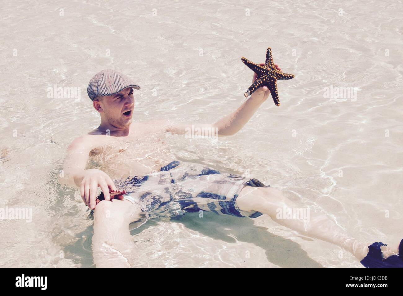 Jeune homme blanc dans l'eau avec une grosse étoile dans sa main. Banque D'Images