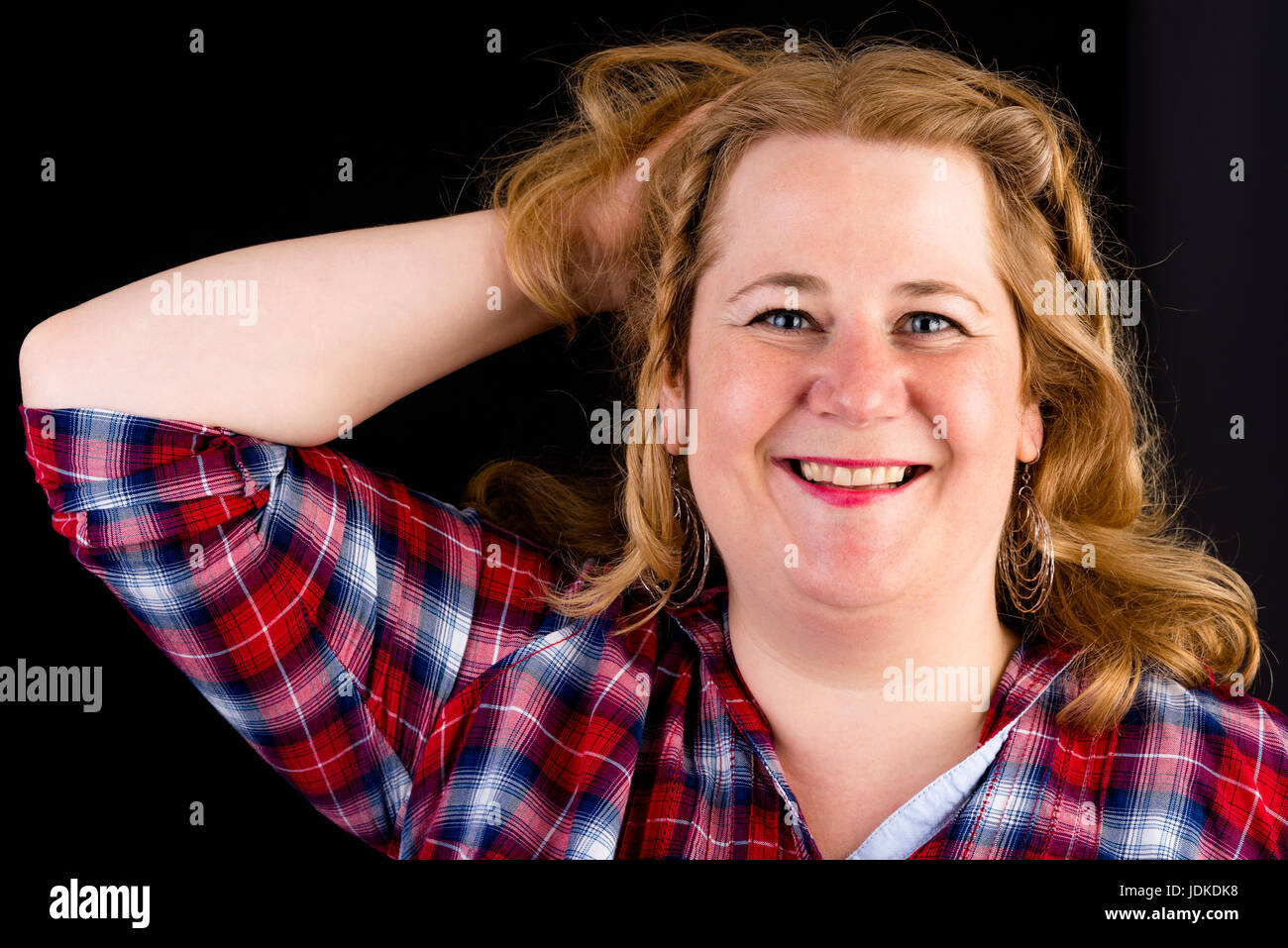 Portrait d'une jolie lumière européenne surpondérés red haired femme rouge avec chemise bûcheron - voir sur la tête, studio shot en face de black backgrou Banque D'Images
