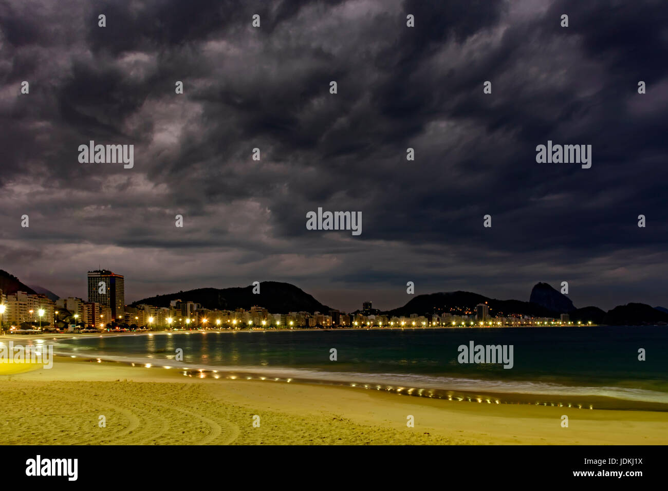 La plage de Copacabana et le Pain de Sucre vu la nuit avec ses bâtiments, l'éclairage, la mer, les collines et les contours Banque D'Images