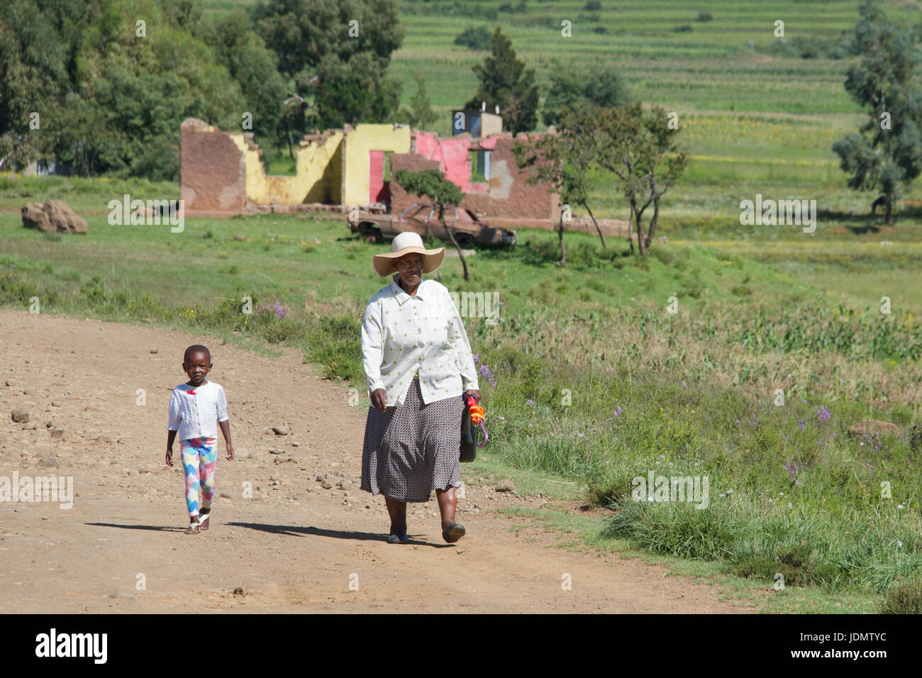 Femme et enfant de marcher le long de la route aby dans brouette Malealea Manzini District Lesotho Afrique du Sud Banque D'Images