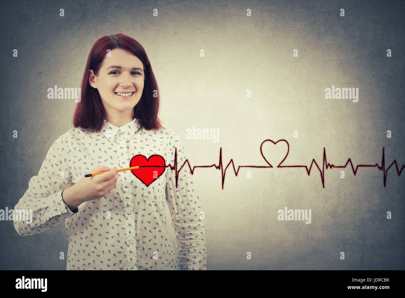 Young Girl smiling, un crayon pour dessiner la poitrine, un cœur rouge avec son cardiogramme heartbeat. La charité, les soins de santé, médecine et don conce Banque D'Images