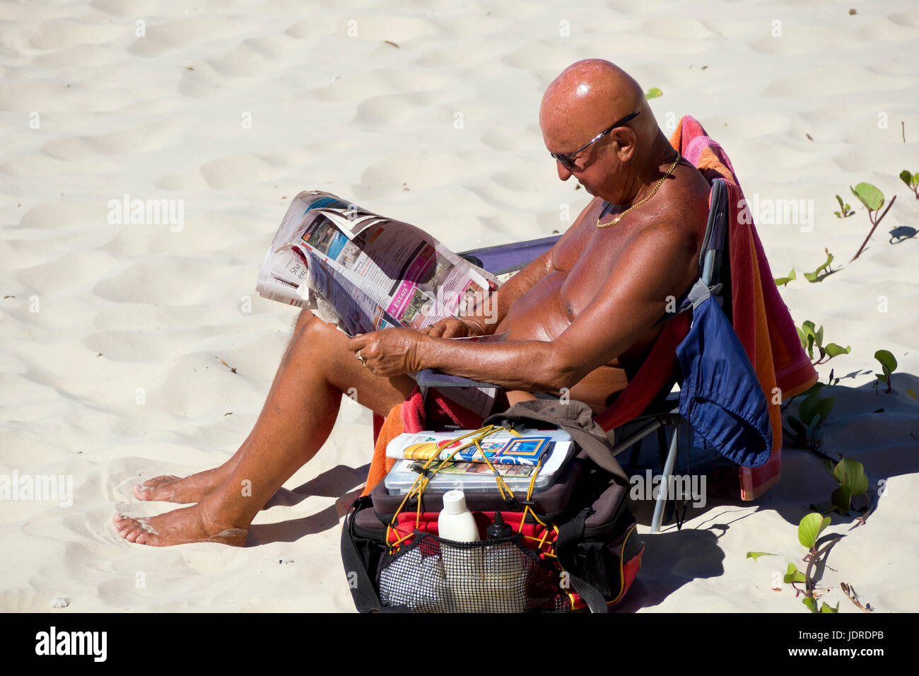 L'homme bronzé journal de lecture à la plage Banque D'Images