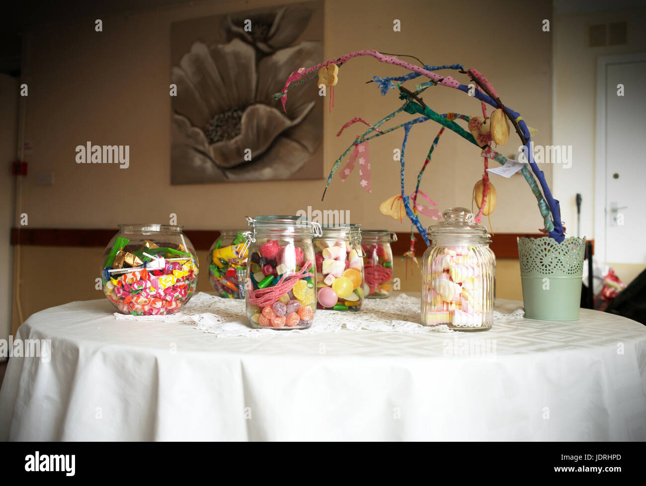 Les bocaux en verre remplis de bonbons à une table avec un tissu blanc Banque D'Images