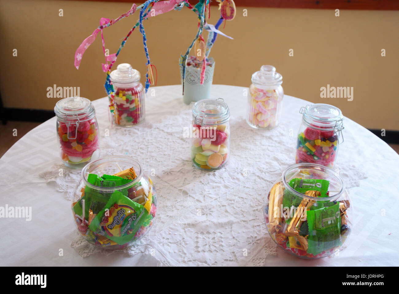 Les bocaux en verre remplis de bonbons à une table avec un tissu blanc Banque D'Images