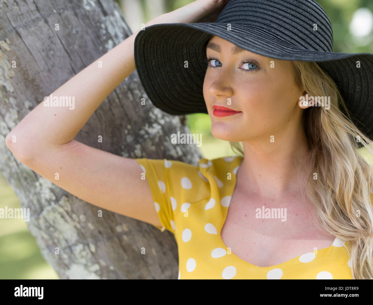 Jeune Australienne femme en robe à pois jaune détente à Palm Cove, près de Cairns, Queensland, Australie Banque D'Images