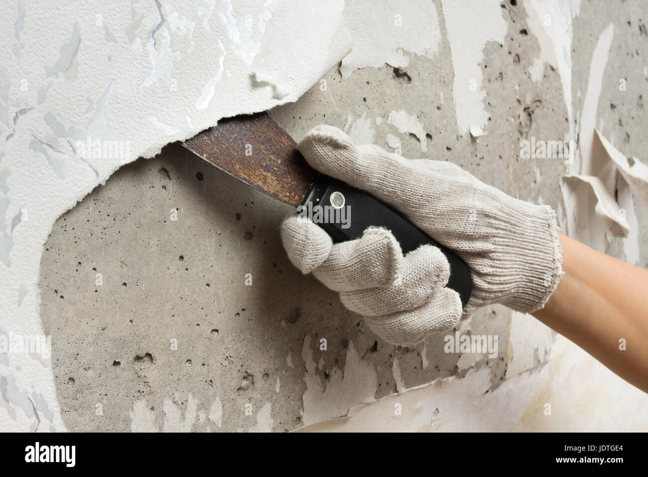 La dépose de l'ancienne à la main à partir de papier peint mur à l'aide d'une spatule pour la réparation Banque D'Images