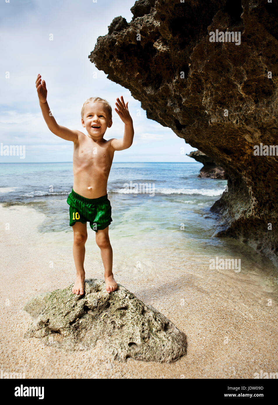 Garçon jouant sur des rochers sur la plage Banque D'Images