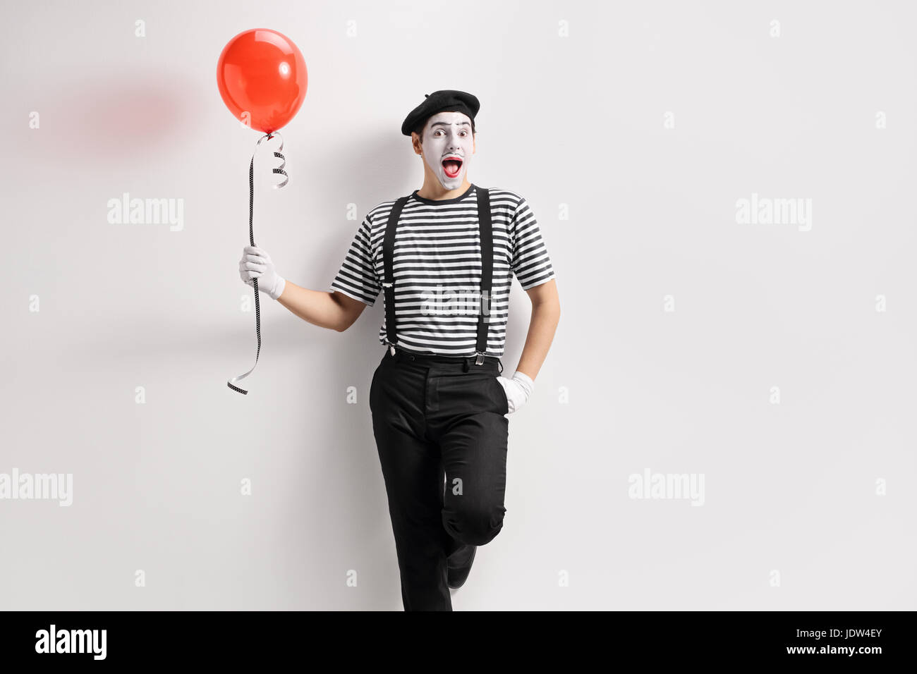 Holding Mime un ballon et appuyé contre un mur Banque D'Images